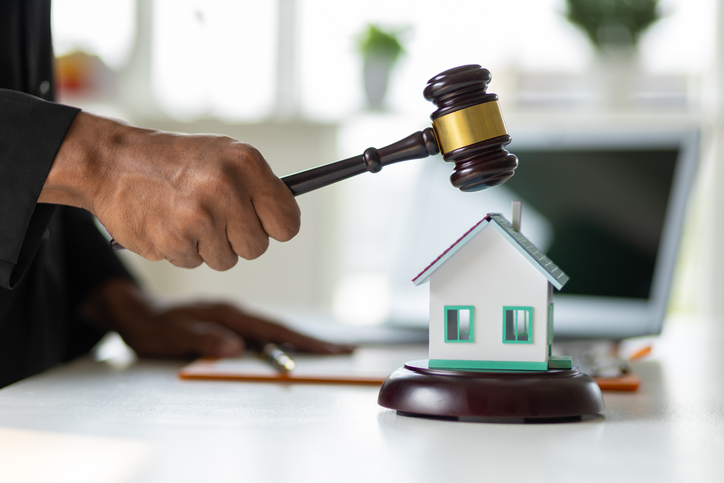 Advocaat slaat met hamer op modelhuis – symbool voor uitspraak in vastgoedgeschil of civiel hoger beroep